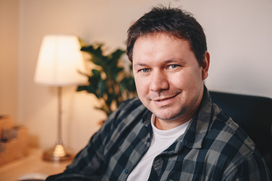 Close up portrait of a handsome young male writer posing in his home office, looking at the camera.