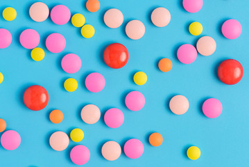 Yellow, red and pink pills or capsules on a blue background