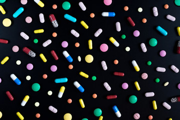 Medicine green and yellow pills or capsules on a black background