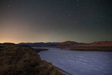 Naklejka na ściany i meble Frozen river and mountain at the starry night.