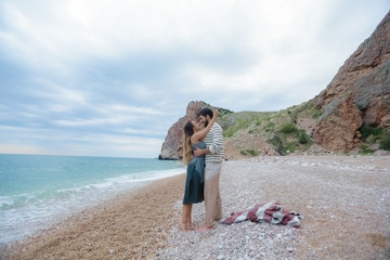 Romantic atmosphere. Happy couple woman and man walking the dog near the sea with mountains in the background.