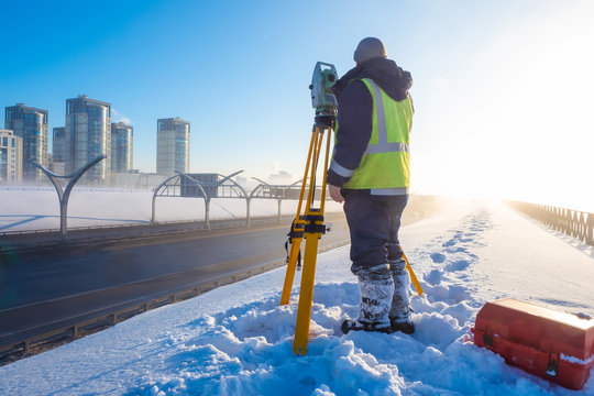 Theodolite. Topographic equipment. Theodolite stands on a tripod. Topographical measurements. Surveyor stands with a tripod. Construction works. Construction measurements. The work of the tapographer.