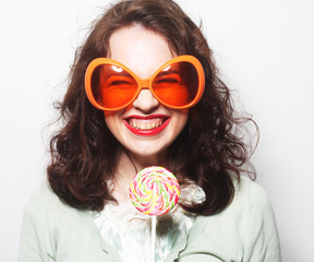  woman in big orange glasses licking lollipop with her tongue