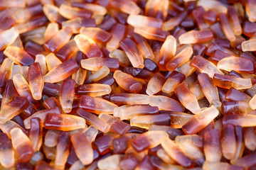 gummy cola bottle candy, yelow and brown background