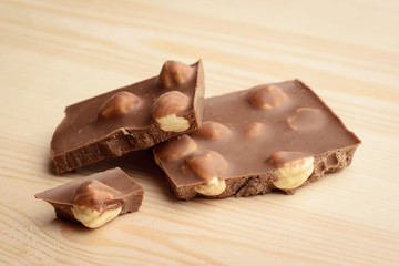 Milk chocolate with nuts on light wooden background