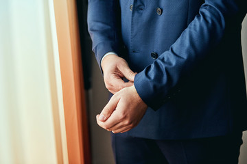 Fototapeta premium Businessman wears a jacket,male hands closeup,groom getting ready in the morning before wedding ceremony. Men Fashion