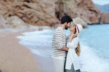 Fototapeta premium Couple in love on a romantic walk on the beach with a dog on a leash. Wearing a warm knit sweater. Romantic concept.