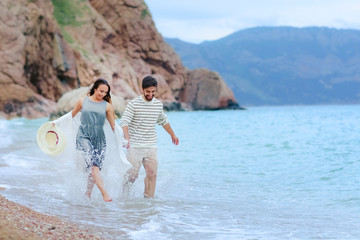 A beautiful romantic couple have a rest  on a beach dressed in warm clothes