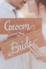 Close up of the bride and groom holding sign wooden plate outdoors. Romantic couple and love concept