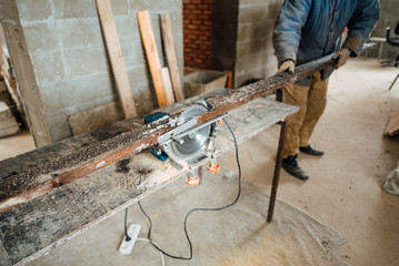 man in work clothes by profession carpenter handles wooden board on circular saw on a wooden...