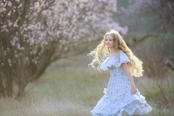 Fototapeta na wymiar Sweet woman in a beautiful dress dancing in a park with long hair