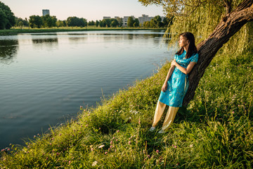 Fototapeta na wymiar Portrait of beautiful Asian Chinese brunette in blue national dress outdoors, young Vietnamese woman in traditional clothes, the girl is resting in park