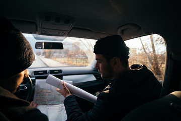 Two violent robbers sitting in a car looking at a blueprint of the building they want to rob while...