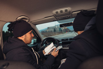 Two happy bank robbers celebrating their successful hit while sitting in the car they used for the...