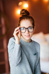 Thoughtful attractive redhead woman bending forwards and looking up to the side with a contemplative expression against a bulbs backgroud