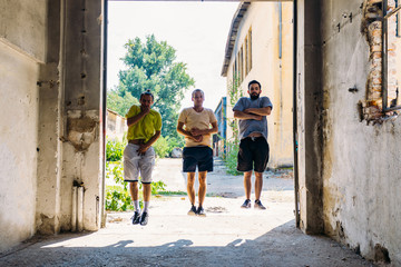 Three attractive sporty young men training parkour outdoor
