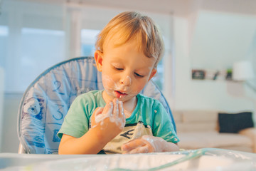 Funny messy baby eating food with his hands
