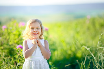 Fototapeta na wymiar Little girl in a blooming field of color. Girl with curly Golden hair