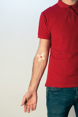 Partial view of patient in red t-shirt with plasters, blood donation concept - obrazy, fototapety, plakaty