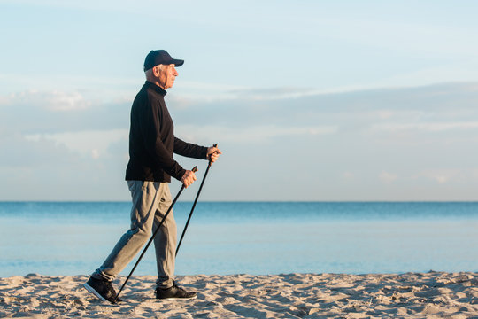 Nordic walking - senior man working out on beach. Healthy lifestyle