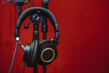 Microphone for recording music and headphones in the studio. Red background.