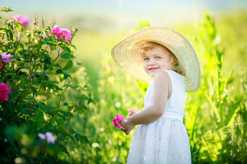 A little girl wearing flower yellow dress with white hat and stand in the yellow flower field of Sunn Hemp Crotalaria Juncea