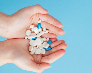 Woman's holding cupped hand full of pills, view from above