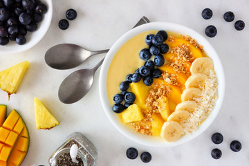 Healthy pineapple, mango smoothie bowl with coconut, bananas, blueberries and granola. Top view...