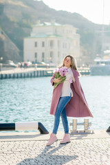 Beautiful happy woman with straight hair holding a bouquet of pink tulips one spring sunny day