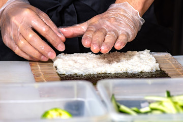 closeup of chef hands rolling up sushi on the kitchen