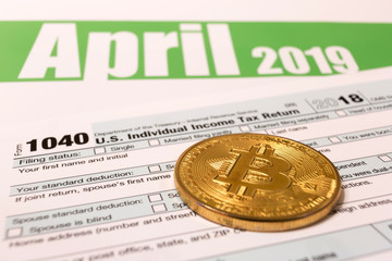 Bitcoin with 1040 income tax form for 2018 showing tax day for filing on April 15