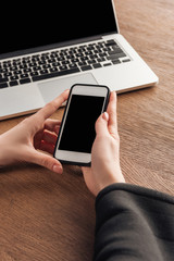 Cropped view of woman posing with smartphone and laptop