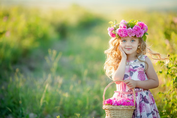A little girl with beautiful long blond hair, dressed in a light dress and a wreath of real flowers...