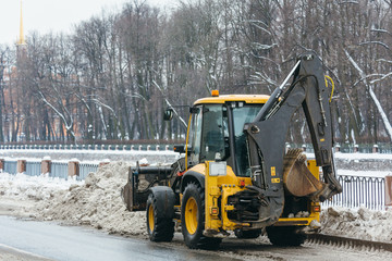 Yellow snowblower clears snow from the street after a big snowstorm, shoveling snow in the ladle/ snowy winter, snowthrower, during a blizzard, snow removal car, equipment for cleaning, winter concept