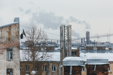 Outdoor panoramic urban photo of steam from the ventilation pipe against the roofs of houses/ smoke...