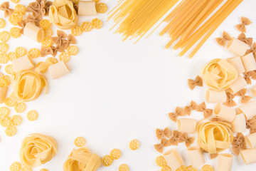 An overhead photo of different types of pasta, including spaghetti, penne, fusilli, and others, flay lay on a white background with a place for text