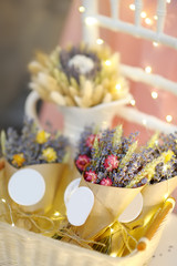 Beautiful dried flowers in paper boxes with lights on background. Wedding decorations close up
