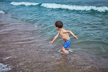 Fototapeta premium Kids playing on sea side beach with blue water clowdy day at Antalya