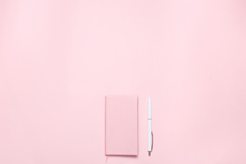 Pink colored desk with pink colored diary and white pen. Minimalistic flat lay composition with copy space for bloggers, designers, magazines etc.
