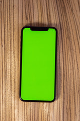 Luxury smartphone on wooden luxury background with green chroma key display copy space to insert...