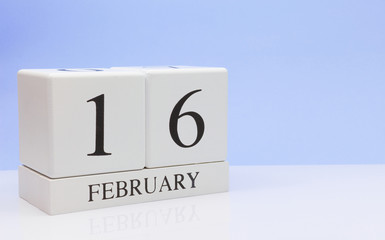 February 16st. Day 16 of month, daily calendar on white table with reflection, with light blue background. Winter time, empty space for text