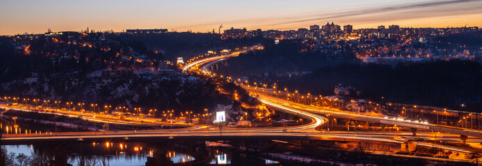 View of Barrandov Bridge over Vltava River in Branik, Prague, Czech Republic. Illuminated roads in cold winter evening