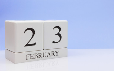 February 23st. Day 23 of month, daily calendar on white table with reflection, with light blue background. Winter time, empty space for text