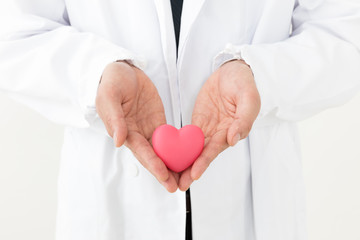 portrait of young asian doctor holding heart symbol isolated on white background