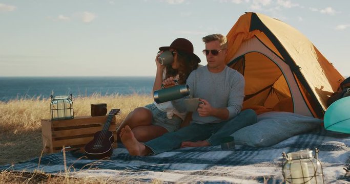 Attractive man pouring beverage and toasting with his partner, summer surf camping adventure