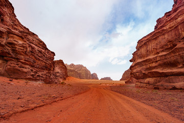 Wadi Rum desert, Jordan, Middle East, The Valley of the Moon. Orange sand, haze, clouds. Designation as a UNESCO World Heritage Site. Red planet Mars  landscape. Offroad adventures travel background.