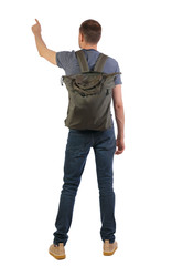Fototapeta premium Back view of a man with a green backpack pointing forward.