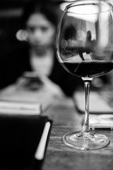 young adult woman busy with her phone behind of a wine glass
