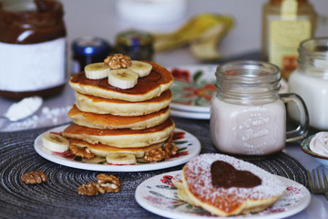 Breakfast pancakes served with honey and fruits and milk