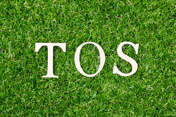 Wood letter block in word TOS (abbreviation of Terms Of Service) on artificial green grass background